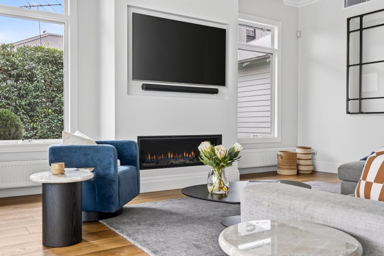 Living room with fireplace and blue armchairs in the Surrey Hills weatherboard home