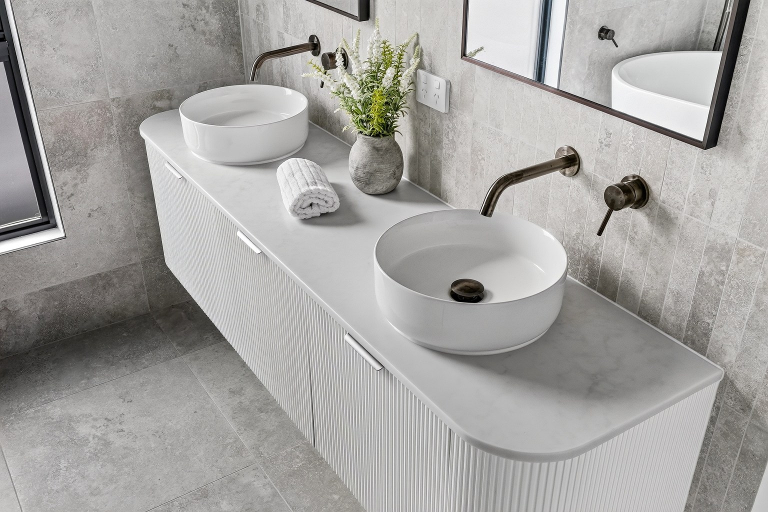 Close view of two vessel basins, wall-mounted tapware and a curved fluted vanity at Kostas Street, Sunbury.