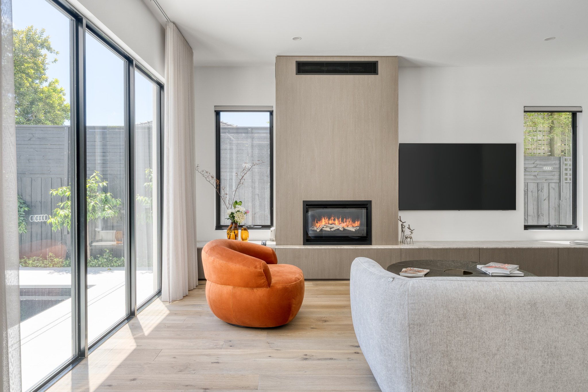 Contemporary Balwyn living room with fireplace, garden glazing and orange armchair