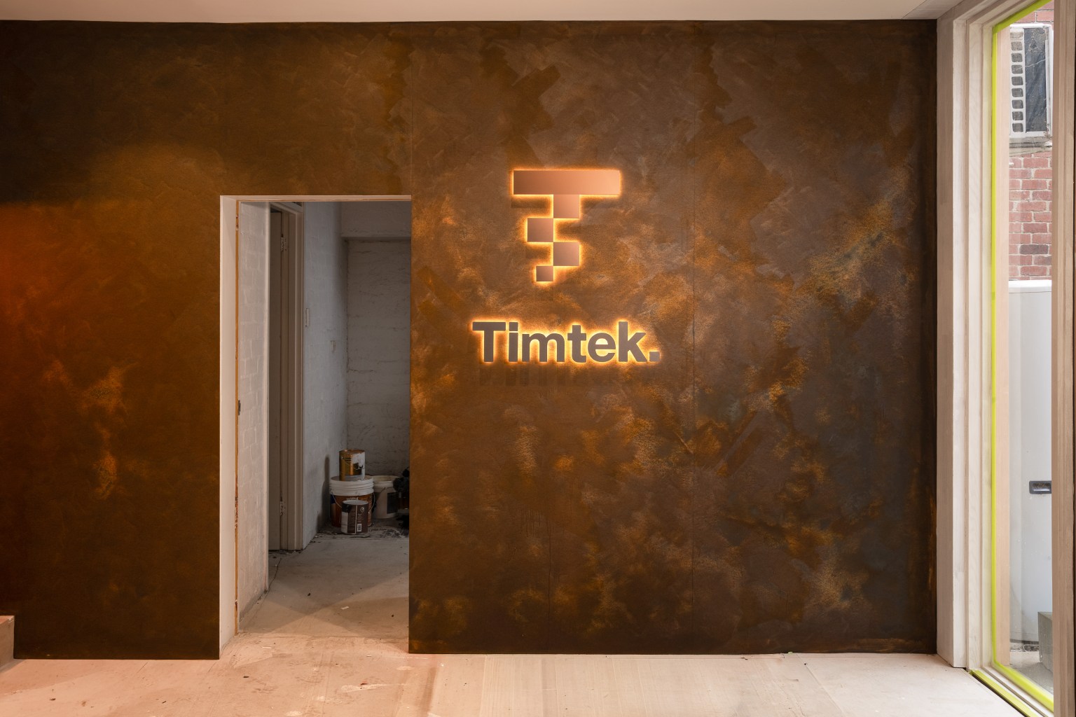 Illuminated Timtek signage on a bronze feature wall during the showroom fit out.