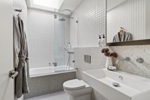 White tiled bathroom with bath and skylight at 1 Carrigal Street